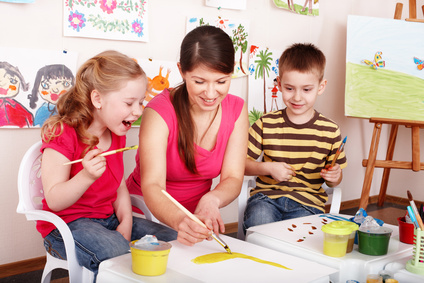 Kindergärtnerin malt mit Kindern ein Bild