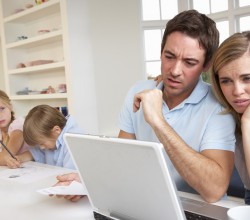 Junges Paar am Laptop, Kinder im Hintergrund